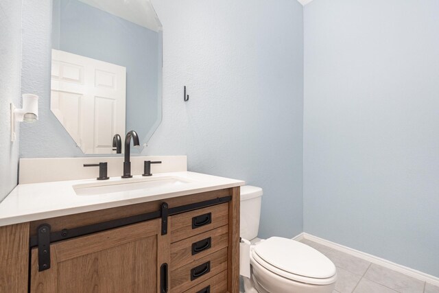 half bathroom with toilet, vanity, tile patterned floors, and baseboards