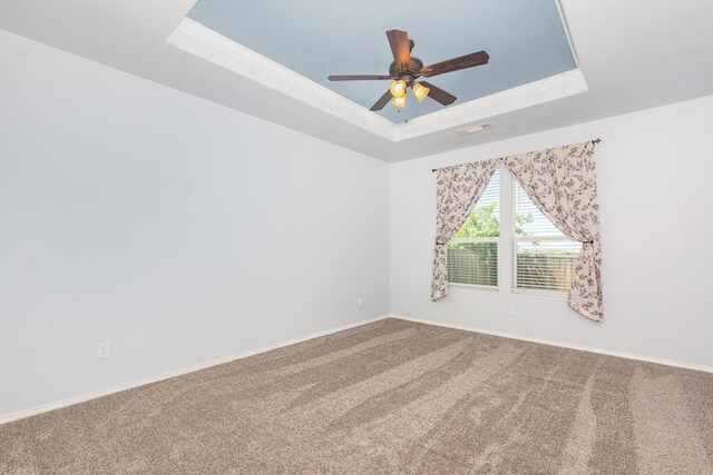 spare room featuring a raised ceiling, carpet, ceiling fan, baseboards, and crown molding