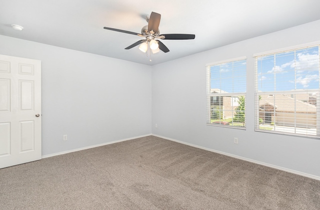 carpeted spare room featuring a ceiling fan and baseboards