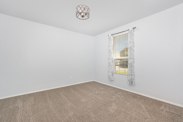 unfurnished room featuring carpet, baseboards, and a chandelier