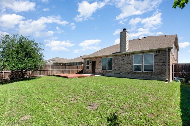 rear view of property with a chimney, brick siding, a deck, and roof with shingles