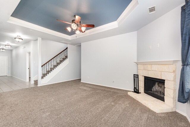 unfurnished living room with a raised ceiling, carpet floors, a ceiling fan, a fireplace, and crown molding
