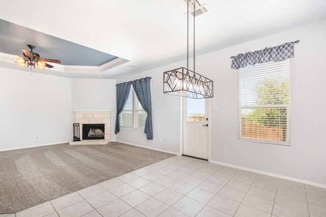 unfurnished living room with a ceiling fan, a fireplace with raised hearth, baseboards, and light carpet
