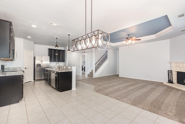 2217 Heaton St, Forney, TX 75126 - kitchen featuring stainless steel appliances, open floor plan, a sink, light tile patterned floors, and dark cabinetry