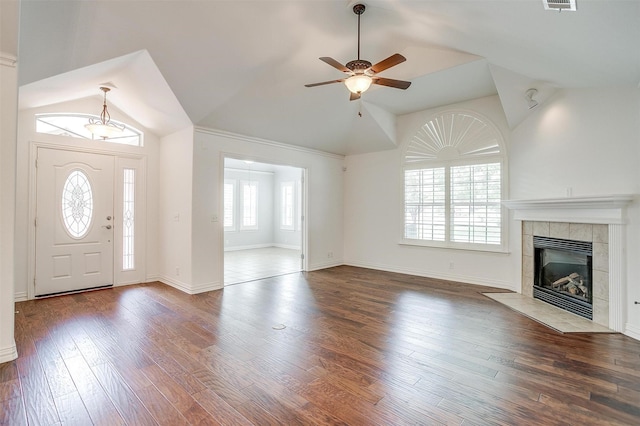 unfurnished living room with lofted ceiling, a ceiling fan, a tiled fireplace, wood finished floors, and baseboards