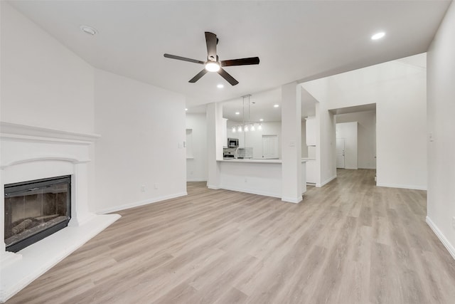 10832 Hawks Landing Rd, Fort Worth, TX 76052 - unfurnished living room with a ceiling fan, light wood-style flooring, a glass covered fireplace, baseboards, and recessed lighting