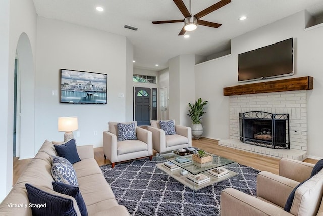 living room featuring ceiling fan, wood finished floors, arched walkways, recessed lighting, and a fireplace