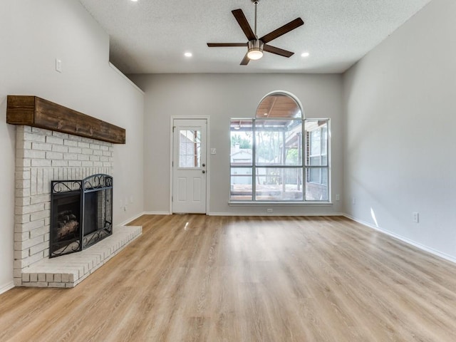 unfurnished living room with a ceiling fan, a brick fireplace, wood finished floors, a textured ceiling, and recessed lighting