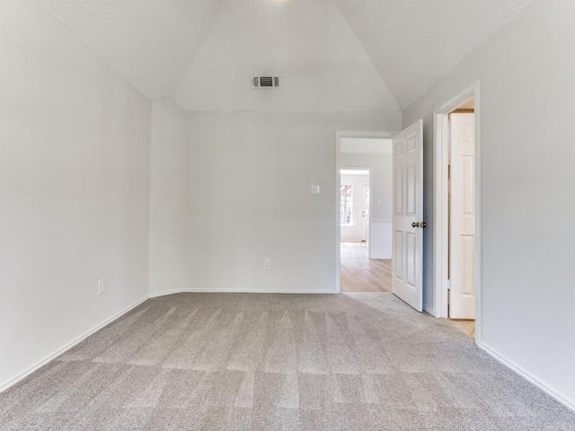 empty room with carpet flooring, lofted ceiling, and baseboards