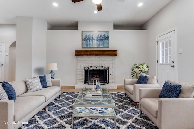 living room with a ceiling fan, recessed lighting, a brick fireplace, wood finished floors, and arched walkways