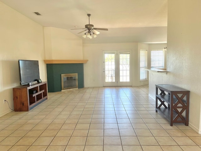 unfurnished living room featuring a glass covered fireplace, ceiling fan, vaulted ceiling, light tile patterned floors, and baseboards