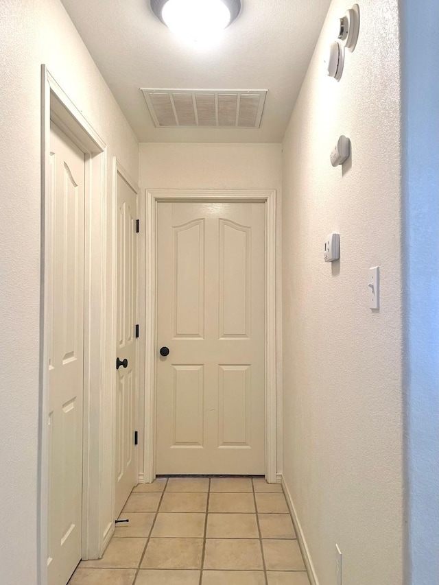 hallway featuring light tile patterned flooring and baseboards