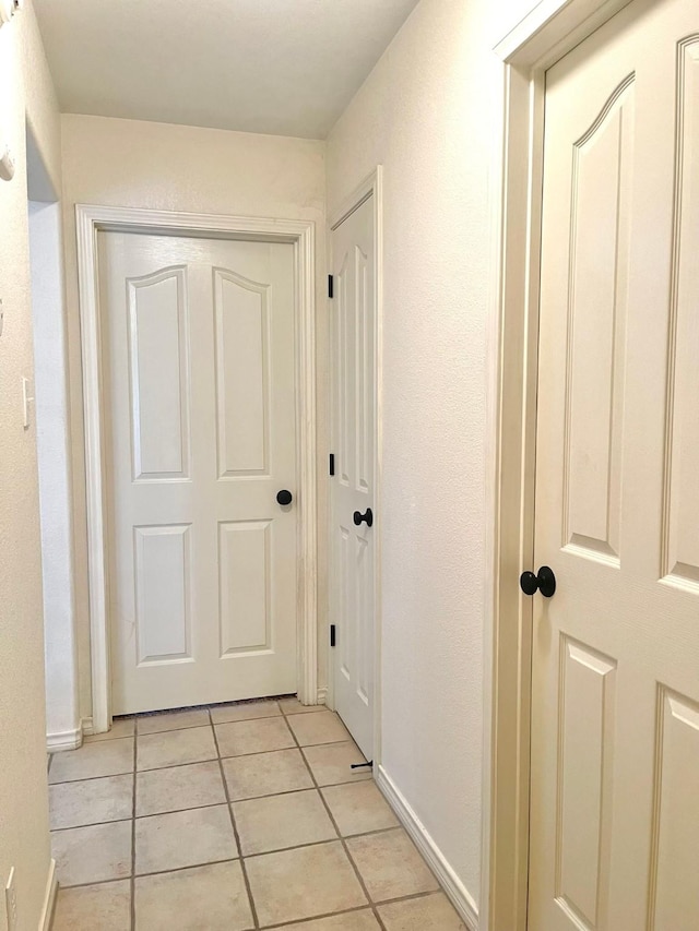hallway with light tile patterned floors and baseboards