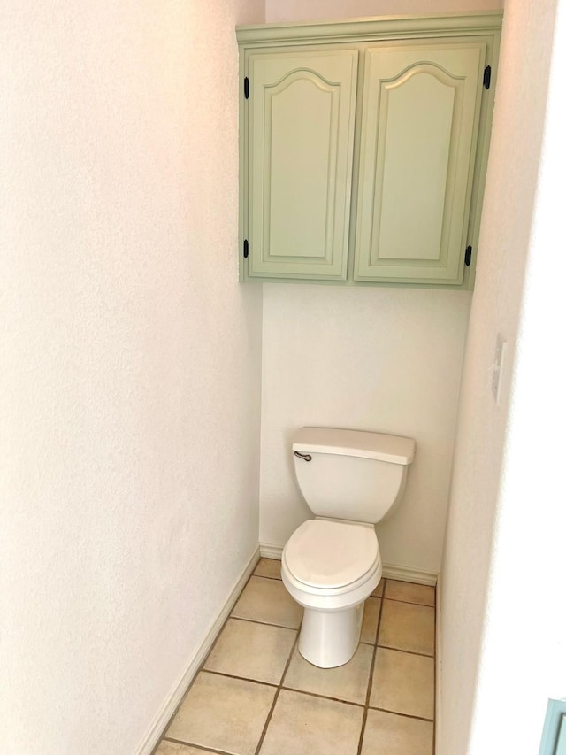 bathroom with baseboards, tile patterned floors, and toilet