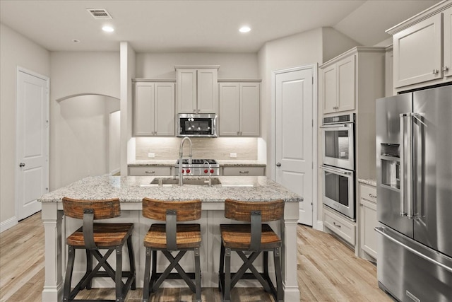 8325 Western, The Colony, TX 75056 - kitchen featuring appliances with stainless steel finishes, light wood-style floors, a kitchen island with sink, a sink, and recessed lighting