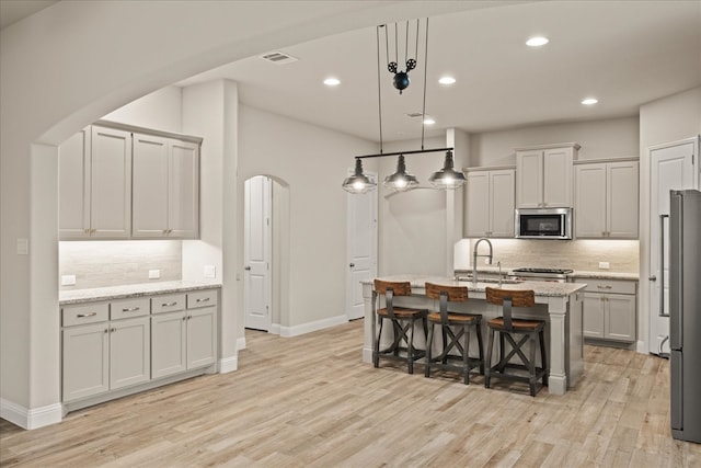 8325 Western, The Colony, TX 75056 - kitchen featuring stainless steel appliances, arched walkways, decorative backsplash, light wood-style floors, and recessed lighting