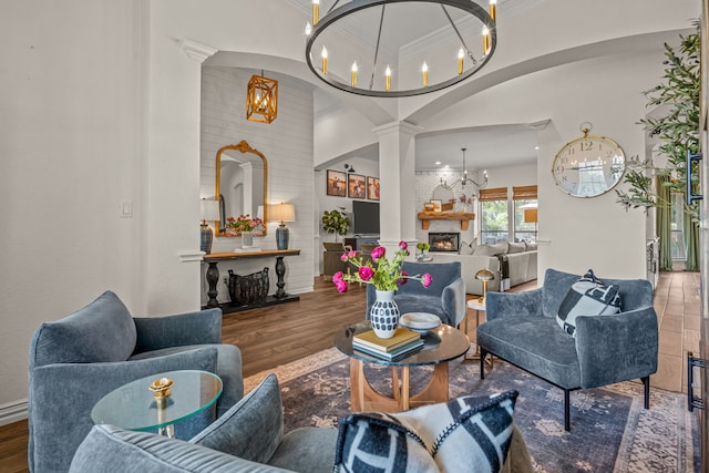 147 Rim Rock Rd, Aledo, TX 76008 - living room featuring a chandelier, ornate columns, ornamental molding, wood finished floors, and arched walkways