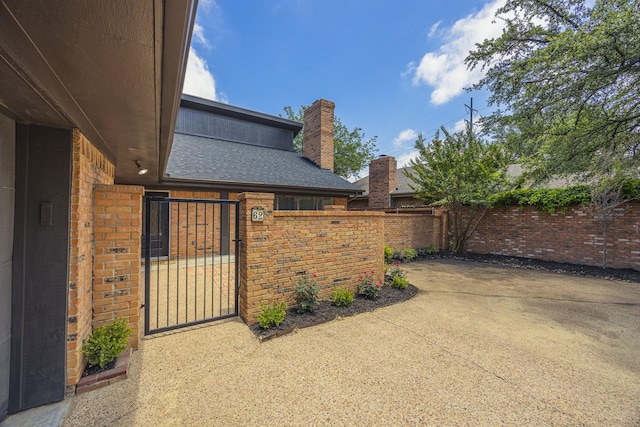 62 Legend Rd, Benbrook, TX 76132 - view of home's exterior featuring a chimney, a gate, brick siding, and a patio area