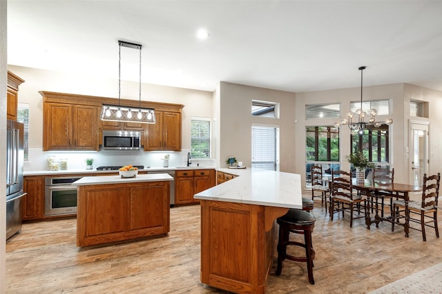 1413 Hunters Ridge Cir, Denton, TX 76205 - kitchen with appliances with stainless steel finishes, a sink, a peninsula, brown cabinetry, and a chandelier