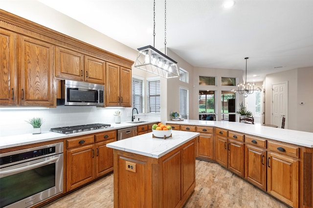 1413 Hunters Ridge Cir, Denton, TX 76205 - kitchen featuring stainless steel appliances, a kitchen island, brown cabinetry, a sink, and a peninsula