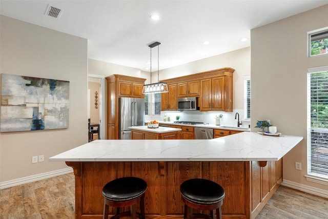 1413 Hunters Ridge Cir, Denton, TX 76205 - kitchen with stainless steel appliances, brown cabinets, light wood-type flooring, light stone counters, and recessed lighting