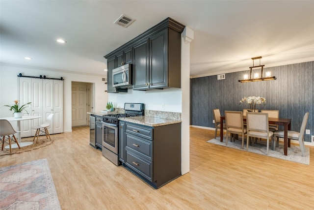 kitchen with appliances with stainless steel finishes, light wood-type flooring, ornamental molding, baseboards, and a barn door
