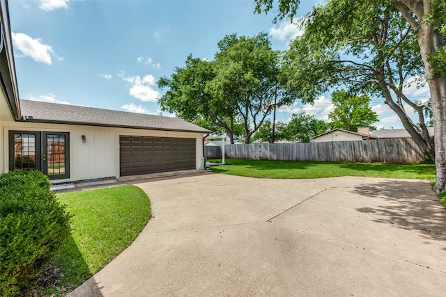 view of yard featuring a garage, driveway, and french doors