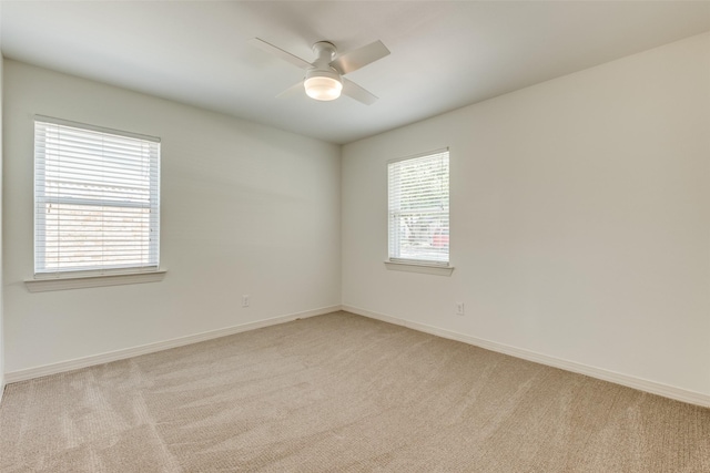 empty room featuring light carpet, a ceiling fan, and baseboards