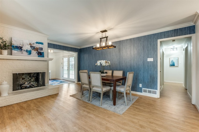 dining area featuring a chandelier, wood finished floors, baseboards, ornamental molding, and a brick fireplace