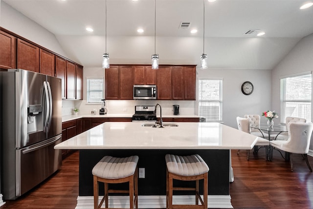 2507 Linwood Dr, Mansfield, TX 76084 - kitchen with appliances with stainless steel finishes, vaulted ceiling, a sink, a breakfast bar area, and light countertops