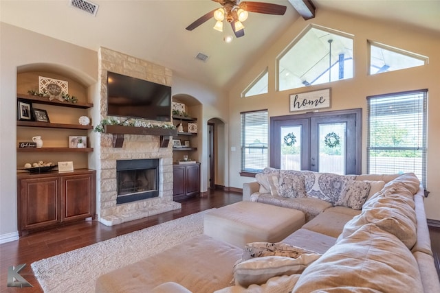 living area with arched walkways, ceiling fan, a stone fireplace, high vaulted ceiling, and dark wood-type flooring