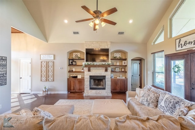 living room with high vaulted ceiling, a ceiling fan, baseboards, a stone fireplace, and arched walkways
