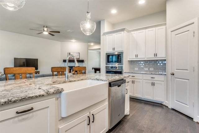 kitchen with stainless steel appliances, a sink, dark wood-type flooring, white cabinetry, and tasteful backsplash