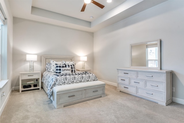 bedroom with light colored carpet, baseboards, a ceiling fan, and a raised ceiling