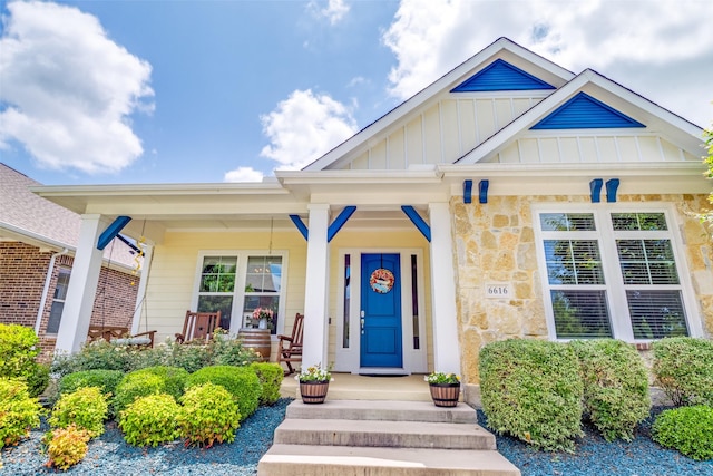 doorway to property with board and batten siding, covered porch, and stone siding