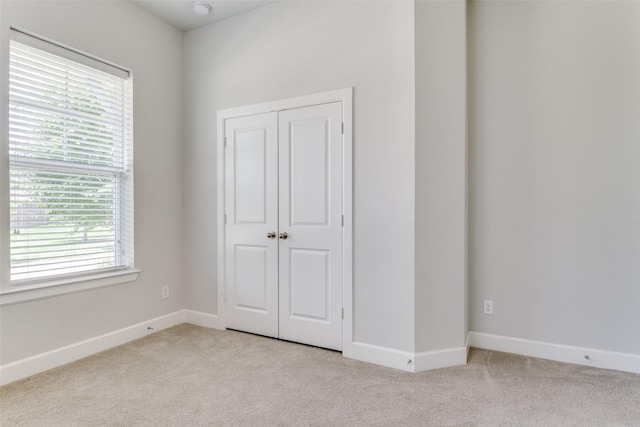 unfurnished bedroom with carpet, multiple windows, baseboards, and a closet