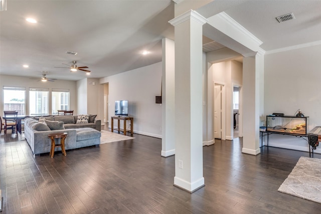living room featuring decorative columns, ceiling fan, baseboards, dark wood-type flooring, and ornamental molding