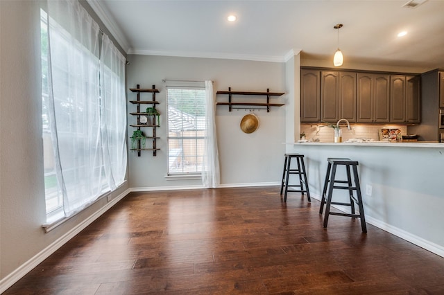 6308 Bittersweet Dr, Arlington, TX 76001 - kitchen with ornamental molding, a breakfast bar, tasteful backsplash, light countertops, and dark wood-style flooring