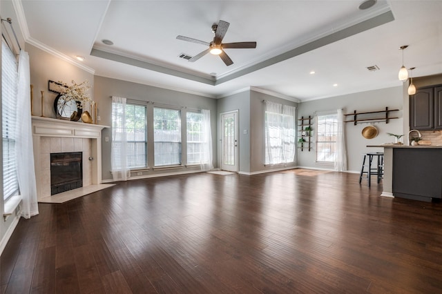 6308 Bittersweet Dr, Arlington, TX 76001 - unfurnished living room featuring a ceiling fan, a raised ceiling, dark wood-style floors, crown molding, and a fireplace