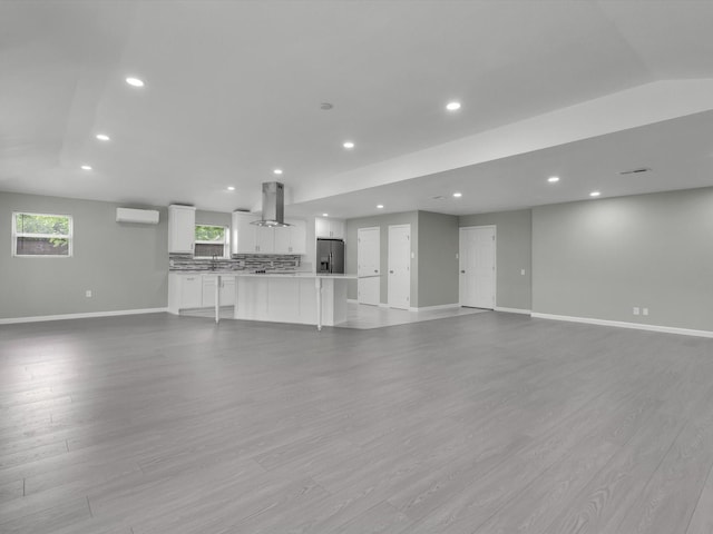 2834 Sunny Hill Ln, Farmers Branch, TX 75234 - unfurnished living room featuring baseboards, an AC wall unit, recessed lighting, and light wood finished floors