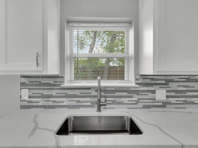 2834 Sunny Hill Ln, Farmers Branch, TX 75234 - kitchen view of a sink, backsplash, white cabinetry, and light stone countertops