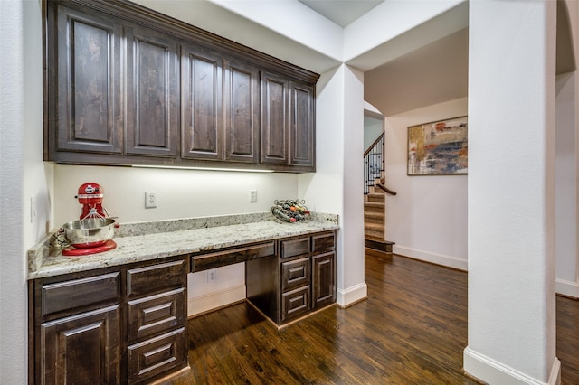 bar area with built in desk, baseboards, dark wood-style flooring, and stairs