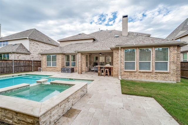 rear view of house featuring a patio area, a fenced backyard, brick siding, a pool with connected hot tub, and a chimney