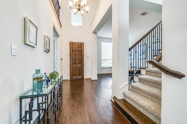 foyer featuring a chandelier, dark wood-type flooring, stairs, and baseboards