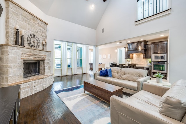 living area featuring high vaulted ceiling, dark wood finished floors, and a fireplace