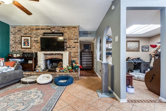 2818 Ashglen Dr, Garland, TX 75043 - tiled living area with a ceiling fan, arched walkways, a brick fireplace, and baseboards