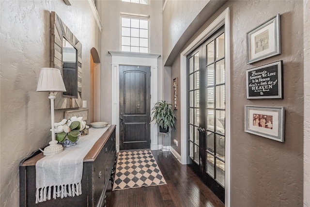 1212 Teton Dr, Burleson, TX 76028 - foyer entrance featuring dark wood-type flooring, a textured wall, arched walkways, baseboards, and french doors
