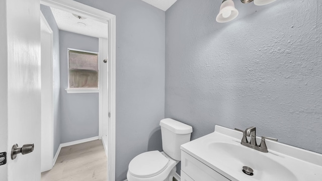 2017 Moline Dr, Haltom City, TX 76117 - half bathroom featuring wood finished floors, toilet, vanity, and baseboards