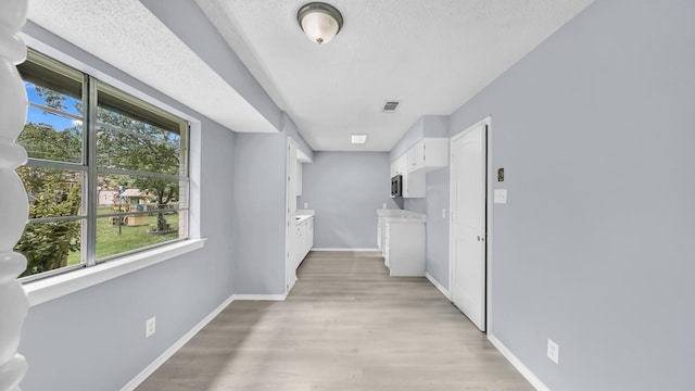 2017 Moline Dr, Haltom City, TX 76117 - hallway featuring baseboards, light wood-style floors, and a textured ceiling