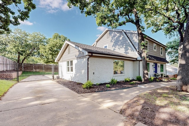 53 Devonshire Dr, Bedford, TX 76021 - view of home's exterior featuring a gate, concrete driveway, fence, brick siding, and roof with shingles